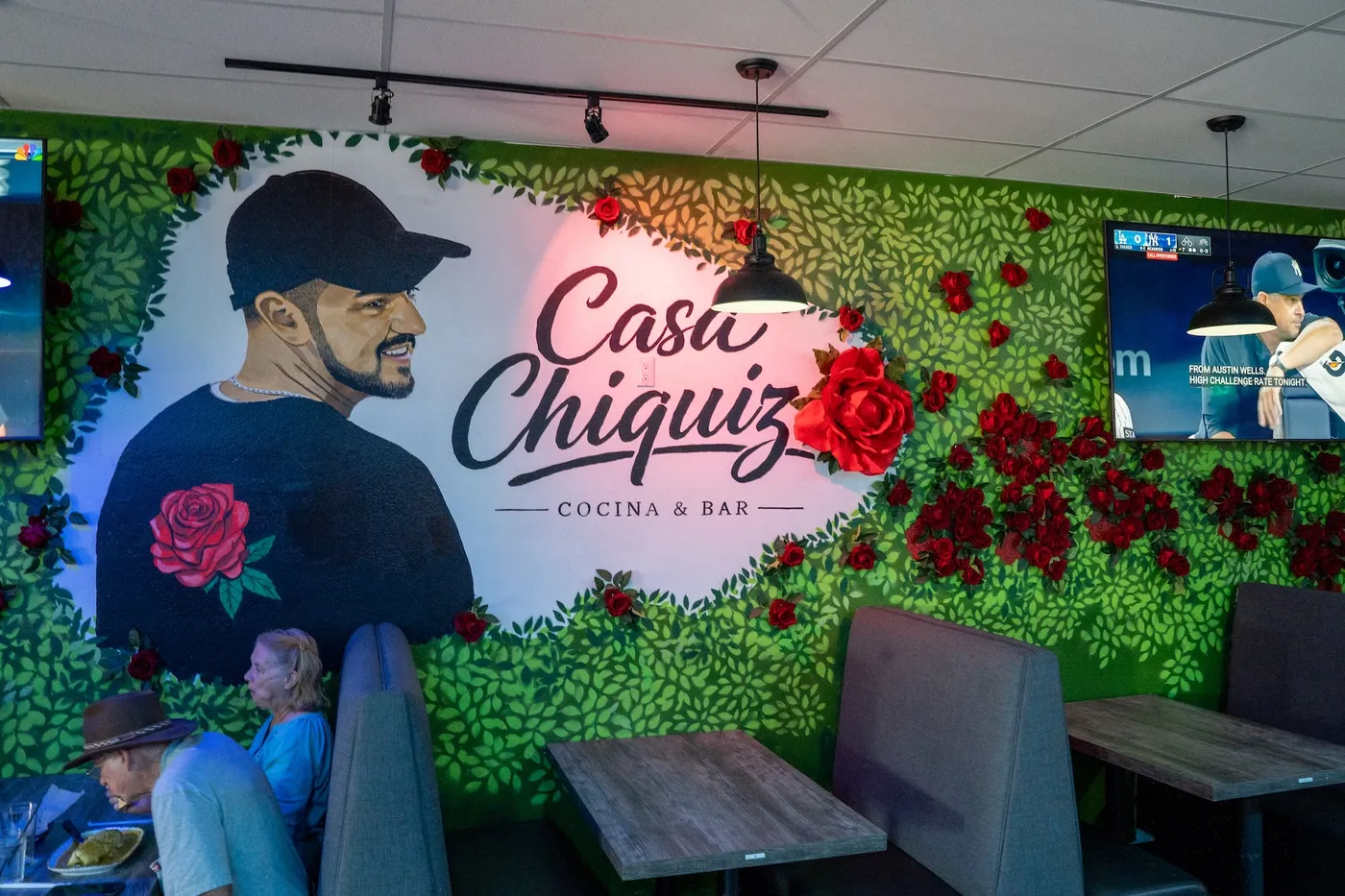 Hand-painted rose wall mural with the Casa Chiquiz logo above the booths